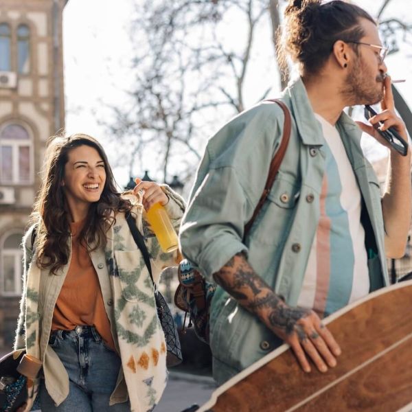 Młoda kobieta i mężczyzna ze skateboardami rozmawiają i śmieją się na ulicy – przyjaźń damsko-męska a znaki zodiaku