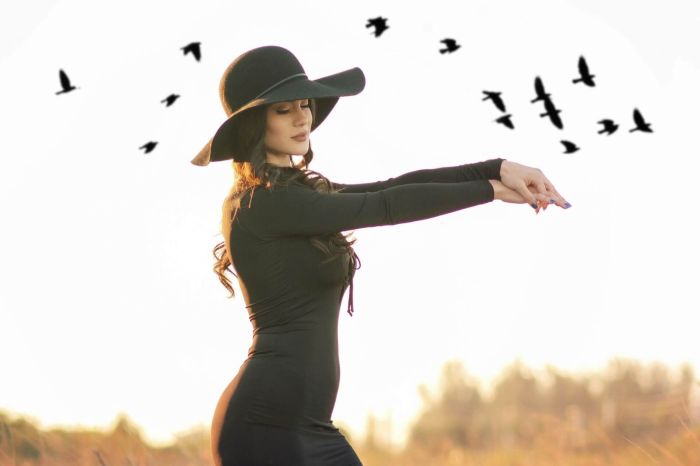 Kobieta w czarnym kapeluszu i sukience na tle nieba z lecącymi ptakami – wiosenne wróżby i ornitomancja