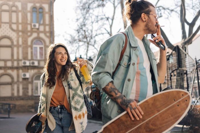 Młoda kobieta i mężczyzna ze skateboardami rozmawiają i śmieją się na ulicy – przyjaźń damsko-męska a znaki zodiaku